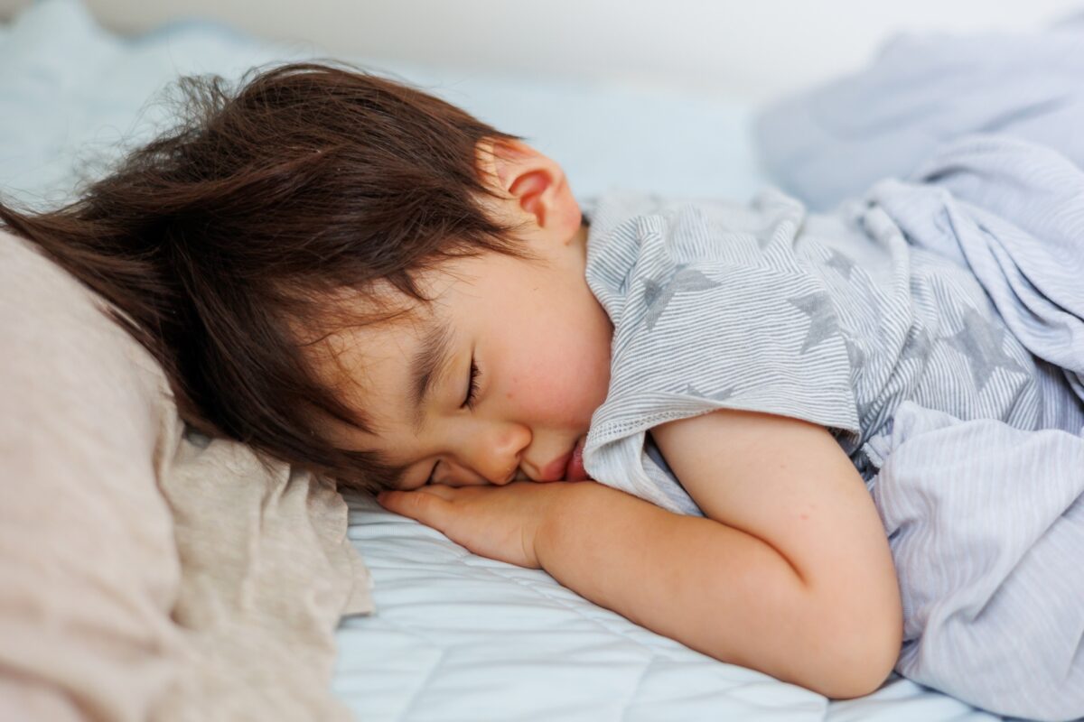 清潔なマットレスで、スヤスヤと気持ちよさそうに眠る幼い子どもの写真。