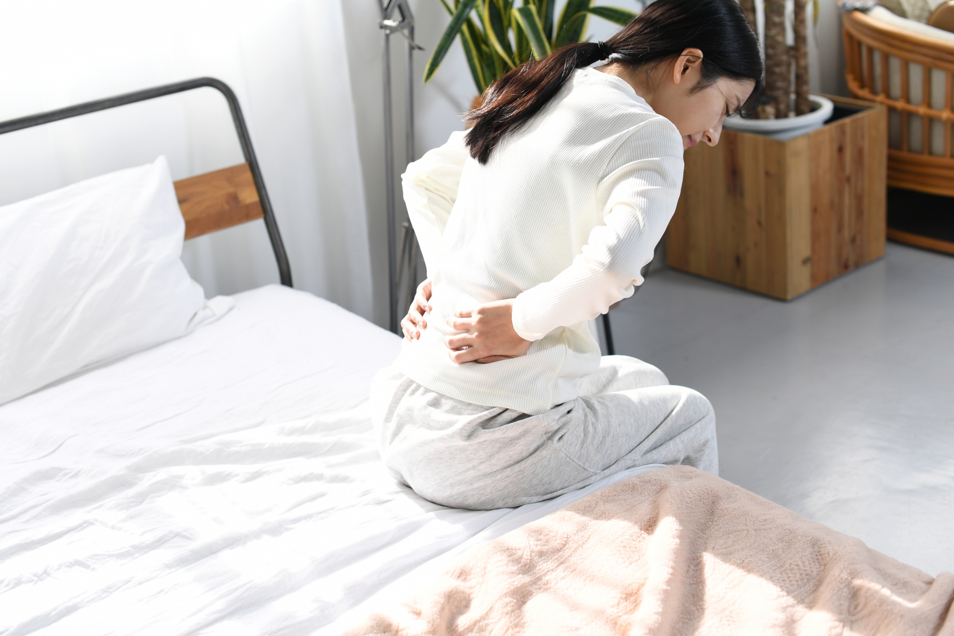 ベッドの上で腰痛に悩む女性